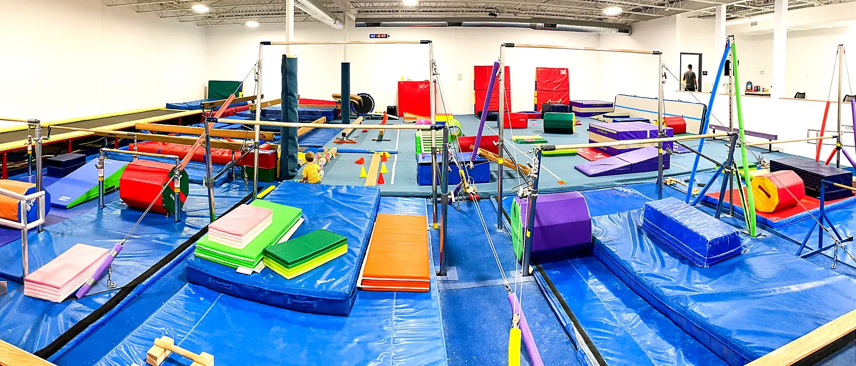 Inside the South Minneapolis gym — bars and blue mats across the training floor
