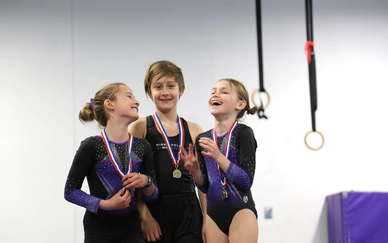 Young team gymnasts in matching leotards celebrate together wearing medals